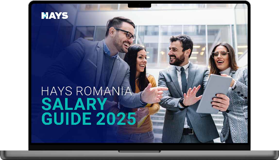 A laptop screen displays the “Hays Hungary Salary Guide 2025” cover featuring a close-up of hands interacting with digital interfaces displaying data graphs and user profiles on a blue background.